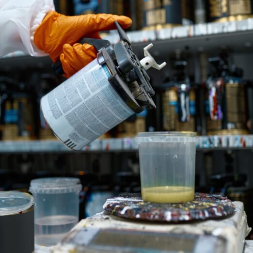 Painter hand holding spray can for car paint preparation. Weighing ingredients process